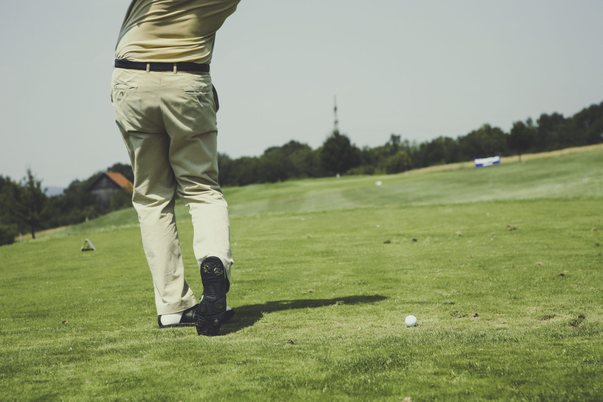 Golfer completing a tee shot on a fairway, showing the rotational load on the back, hips, and shoulders that sports massage in Billings Montana helps manage for golfers and rotational athletes.