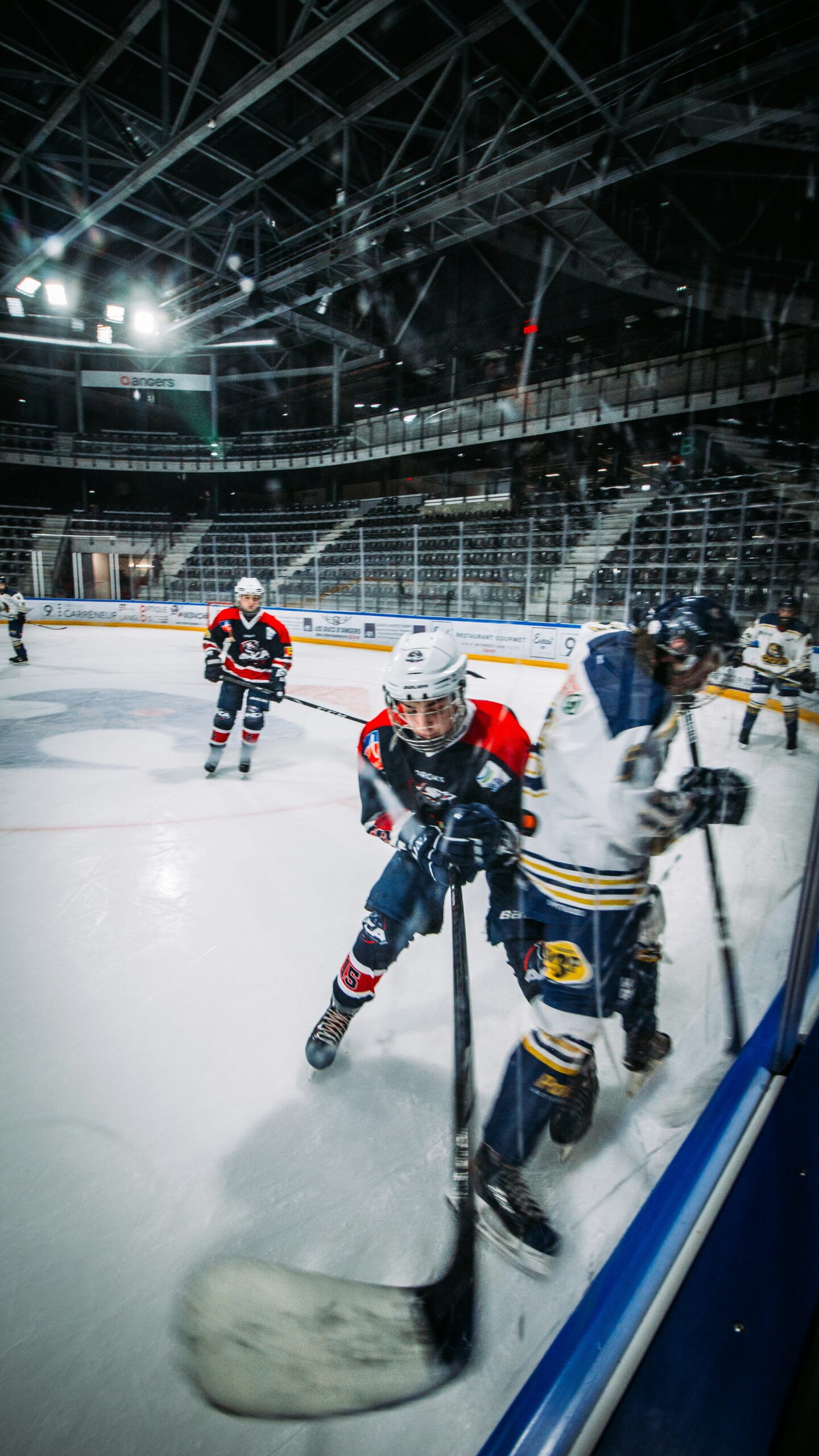 Hockey players colliding along the boards during a game, highlighting the intense contact, fast skating, and lower-body strain that sports massage in Billings Montana helps address for competitive ice-hockey athletes.